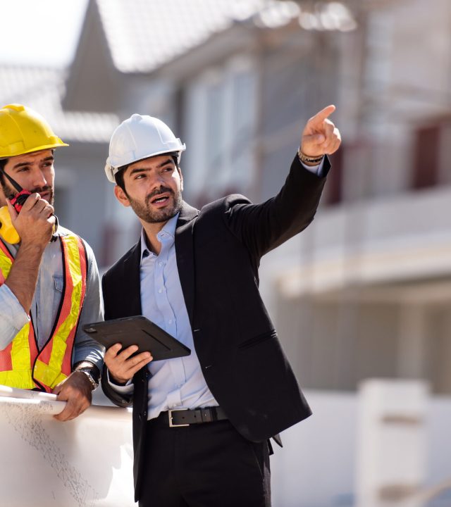 Civil engineer and construction architecture worker are working in construction site with tablet and blueprints for planing about new construction site.Cooperation teamwork concept.